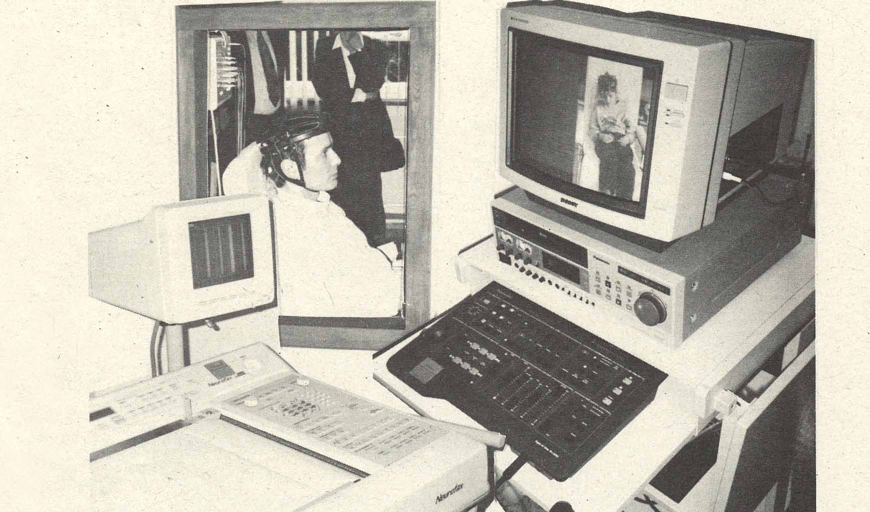 Ein Patient sitzt in einem Raum, davor steht ein Computermonitor, ein Videorekorder und ein EEG-Ableitungs Drucker