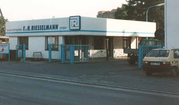 eine Werkseinfahrt, auf dem Gebäude steht Kunststofftechnik F.&H. Riesselmann GmbH