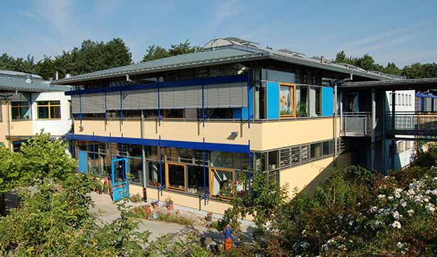 Blick auf die neue Werkstatt, große Fensterfront, gelb und blau gestaltete Fassade