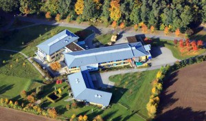 aus der Luft fotografiert: die drei Gebäude der neuen Werkstatt, das bläuliche Dach ist sehr markant