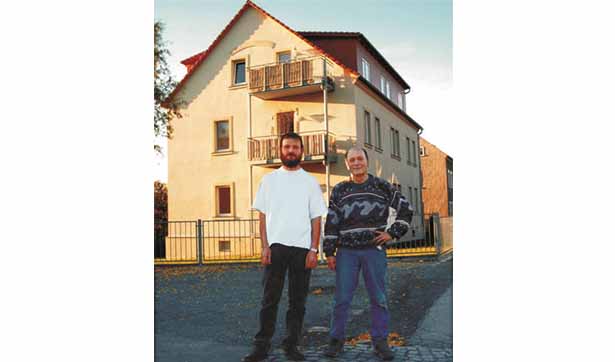 zwei Männer stehen vor dem dreigeschössigen Gebäude