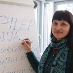 Dr. Polina Sediene steht vor einem Flipchart, auf das sie gerade EPILEPSIJA geschrieben hat, was litauisch für Epilepsie steht